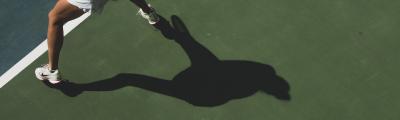 tennisser met haar eigen schaduw op de tennisbaan
