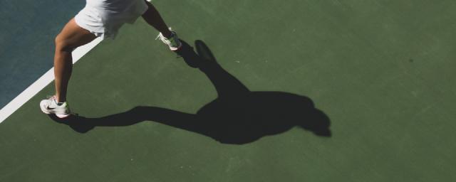 tennisser met haar eigen schaduw op de tennisbaan