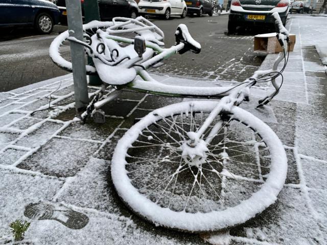 fiets ligt op straat, bedekt door een laagje sneeuw