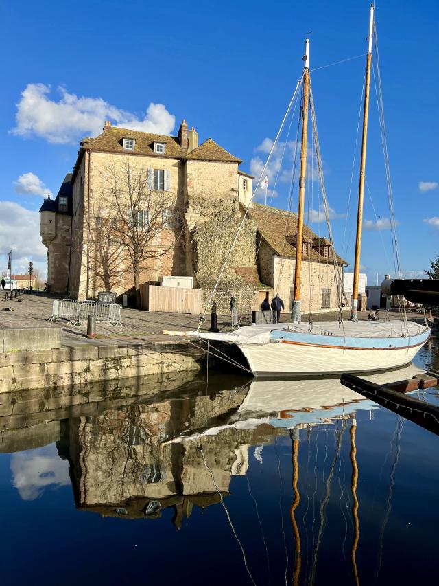een zeilboot in de haven van Honfleur, onder een strak blauwe lucht