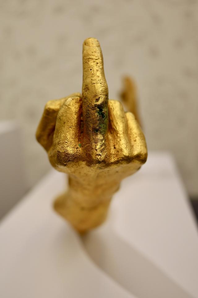 beeld van een gouden hand met opgestoken middelvinger